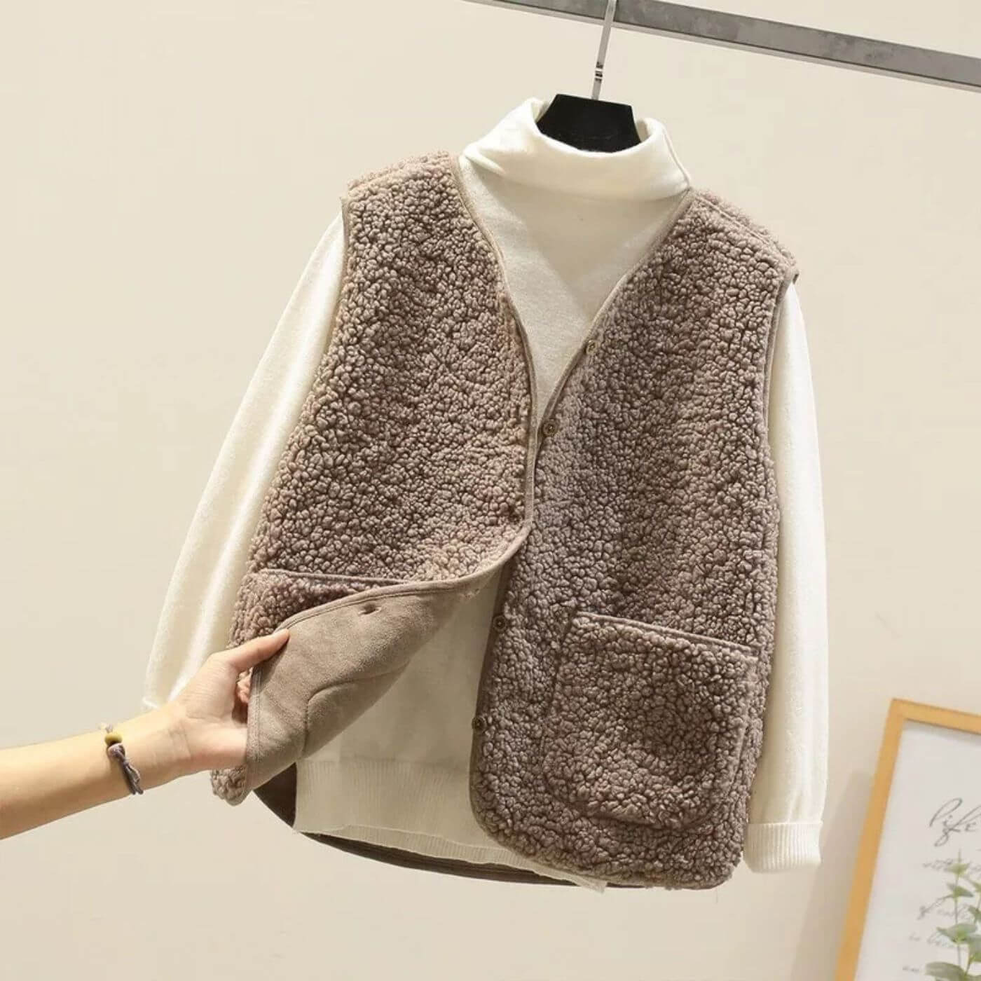 Gilet marron en fausse fourrure sur un col roulé blanc, avec des poches avant et une texture douce.