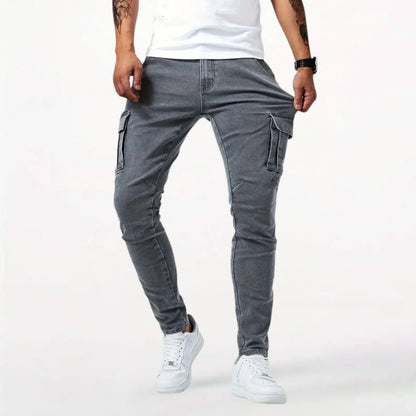 Pantalon cargo gris ajusté pour homme avec poches multiples, porté avec des baskets blanches.